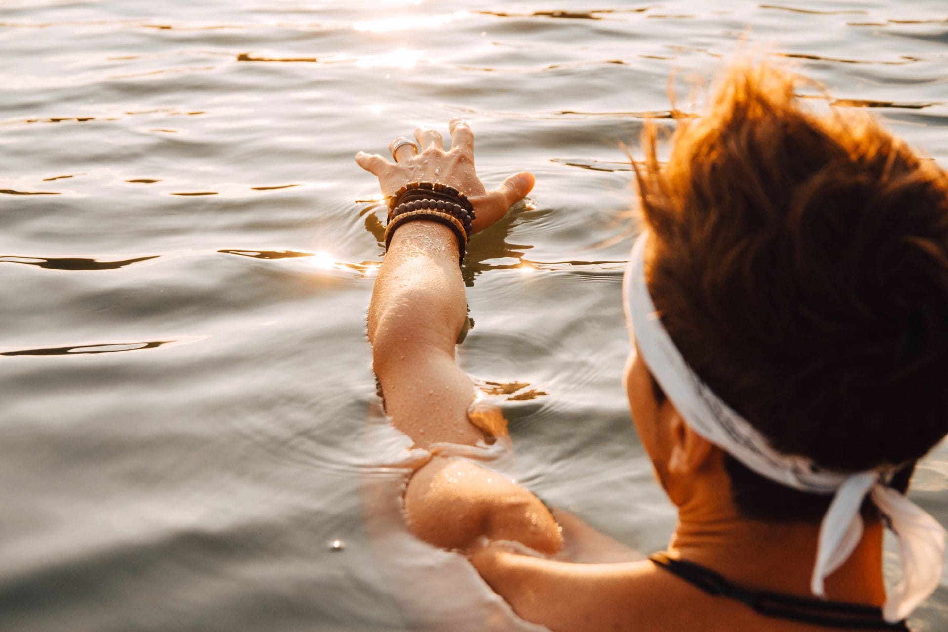 Man touches the water with his hand at sunset. Concept of freedo